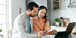 Couple reviewing their credit score print out, managing personal finances at home.